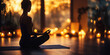 © syhin_stas - Woman is practicing yoga and meditating in her living room in the evening, sitting in lotus position on a yoga mat, surrounded by candles