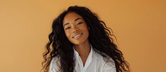 Poster - A young black woman with long curly hair in a white shirt smiles at the camera against a light orange background in the copy space image