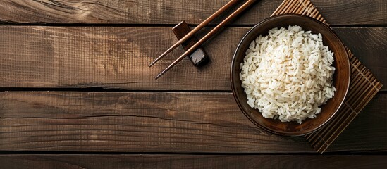 Sticker - A delicious bowl of cooked rice with chopsticks on a wooden table suitable for adding text in the empty area of the image. Creative banner. Copyspace image