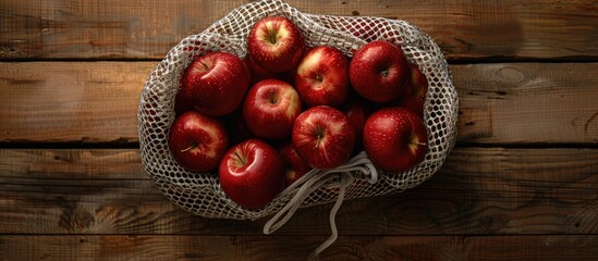 Poster - Top view of a wooden background holding freshly arranged red apples in a grid bag perfect for a copy space image