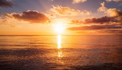 Wall Mural - sun setting below a calm ocean horizon golden sky reflective water rich clouds slight lens flare dreamy atmosphere