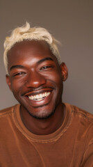 A smiling man with blonde hair and a brown shirt