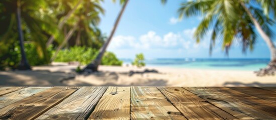 Poster - Empty wooden table in foreground against a blurry tropical beach backdrop with coconut palms ideal for showcasing summer products in a copy space image