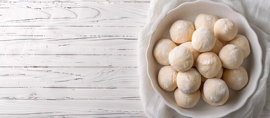 Aufkleber - Top down view of scrumptious dough balls in a baking dish on a white wooden surface with ample space for text beside the image