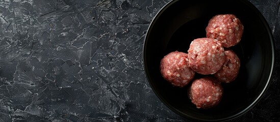 Poster - Food preparation featuring raw ground beef meatballs in a black bowl with copy space image