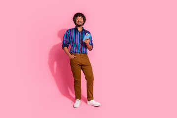 Wall Mural - Photo of cheerful nice man wear stylish striped clothes use gadget isolated on pink color background