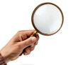 © CozyNessAI - Closeup view of hand holding magnifying glass isolated on white background.