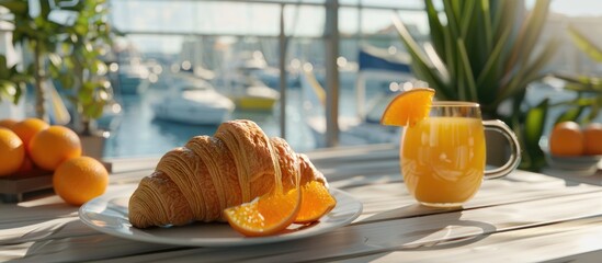 Poster - A European style breakfast with a croissant a glass of juice and fresh oranges on a white wooden table at a marina restaurant offering a copy space image for food and drink items