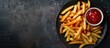 © HN Works - Top down view of homemade American French fries with ketchup on a plate with ample copy space image
