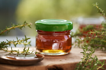 Wall Mural - Thyme herbal syrup in a glass jar with green cap outdoors