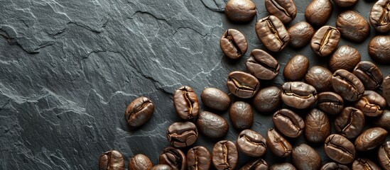 Poster - A top view closeup of freshly roasted coffee beans on a black stone background providing ample copy space for text or images