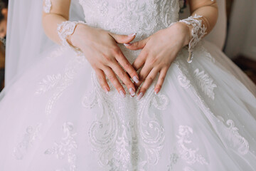 Wall Mural - A woman is wearing a white wedding dress with a diamond pattern. She is holding her hands together in a heart shape