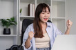 © Natee Meepian - Cheerful Woman Embracing Success During learning in Home
