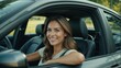 © Ruslan Gilmanshin - A woman is smiling happily while sitting in the drivers seat of her car