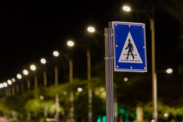 Pedestrian crossing sign at night. Illuminated road sign. City street, night picture. Importance of pedestrian safety at night concept