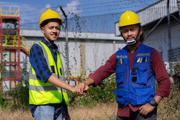 two Asian construction workers shake hands during construction site survey, cooperation agreement, construction work concept.