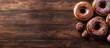 © vxnaghiyev - Assorted donuts on a wooden background viewed from above with empty space for text Chocolate and vanilla frosted donuts adorned with colorful sprinkles Glazed donuts with sprinkles on a wooden surfac