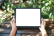 © Sebelas Stock - hands holding a tablet with over a wooden table in the garden