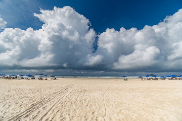 Wall Mural - Morning at Enseada Beach on a beautiful sunny day with some rain clouds around, view of the beach sand and the sea. Guaruja - SP, Brazil.