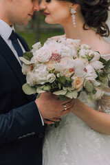 Wall Mural - A bride and groom are holding a bouquet of white flowers. The bride is wearing a white dress and the groom is wearing a blue suit. The flowers are arranged in a vase