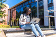 © unai - Focused african university student using laptop sitting on outdoors staircases