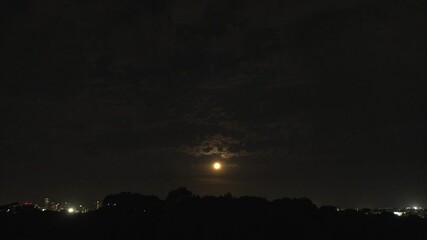 Wall Mural - A small plane flies across the dark night sky over a golden rising moon