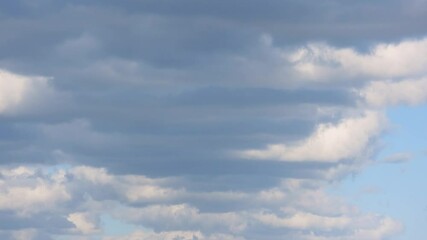 Wall Mural - White clouds slowly move across a blue sky in a peaceful time-lapse