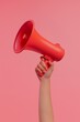© srenhouse - A hand holding a megaphone on a pink background