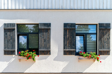 Charming wooden shutters and vibrant flower boxes brighten a modern building's facade in daylight