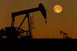 © Designpics - Silhouette of two pumpjacks with a glowing warm sky and full moon, West of Airdrie; Alberta, Canada