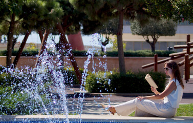 Girl with book in the park on a summer day . High quality photo