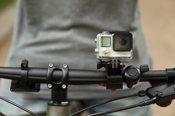 Man riding bicycle with modern action camera outdoors, closeup