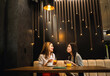 © Mediteraneo - Two girl friends met at the cafe. Drinking coffee and orange juice. They are talking, gossiping and having fun time.