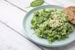 © New Africa - Tasty spinach risotto served with bread on white wooden table, closeup. Space for text