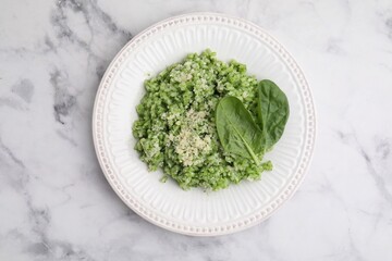 Tasty spinach risotto served on white marble table, top view