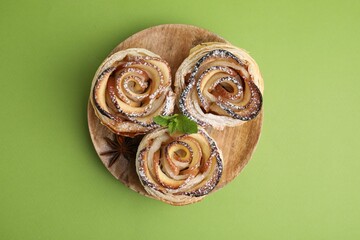 Freshly baked apple roses with mint on green background, top view