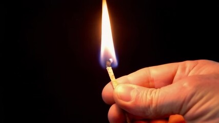 Wall Mural - a hand holds a burning match, creating a dynamic contrast against a dark backdrop, highlighting them