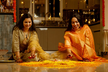 Wall Mural - Smiling Women Celebrating Diwali with Rangoli and Diyas,Women decorating Home on the festival occasion with diya and flowers