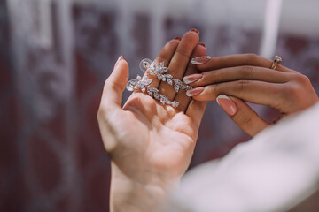 Wall Mural - A woman is holding a pair of earrings in her hand. The earrings are made of diamonds and are very shiny