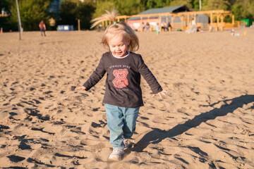 An adorable little toddler is walking along beach, a beautiful landscape and a cute childhood concept. Samara, Russia - 15 June 2024