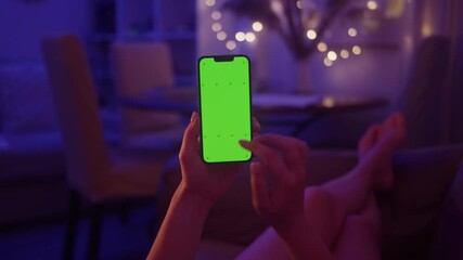 Woman swiping gesture on chroma key of modern smartphone. Person resting at home and using smartphone.