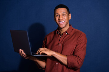 Canvas Print - Photo of funky cool guy dressed brown shirt working modern device emtpy space isolated blue color background