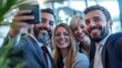 © Andrus Ciprian - Four cheerful colleagues, two men and two women, taking a selfie at a business event.