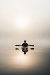 A man kayaking in water in a foggy morning