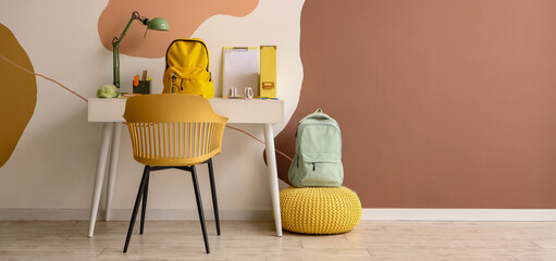 Canvas Print - Workspace with school supplies and backpack near color wall