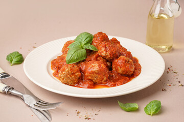 Plate of tasty meat balls with sauce on beige background