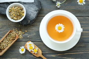 Wall Mural - Cup of hot chamomile tea on dark wooden background