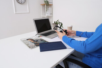 Sticker - Female hands with headphones, modern laptop, notebook and magazine at white table