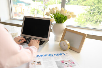 Wall Mural - Woman using laptop at table in office, closeup