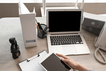 Wall Mural - Woman with tablet computer and laptop at table in office, closeup